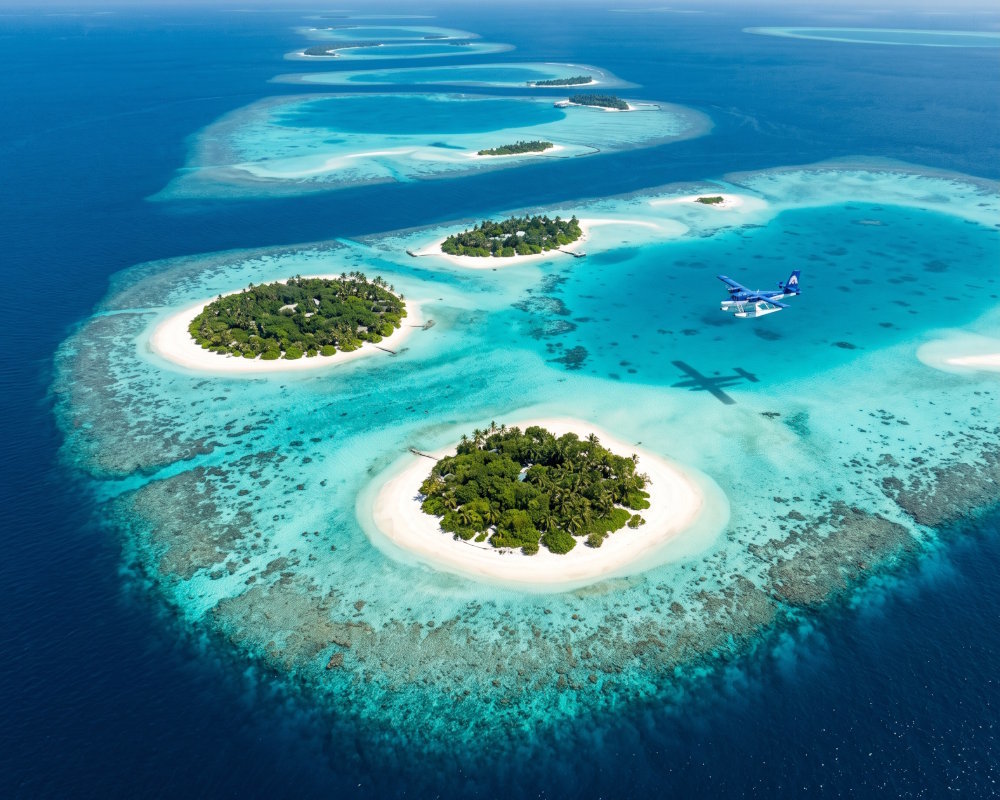 Vue aérienne des atolls des Maldives, avec leurs îles coralliennes, leurs lagon turquoise survolés par un hydravion