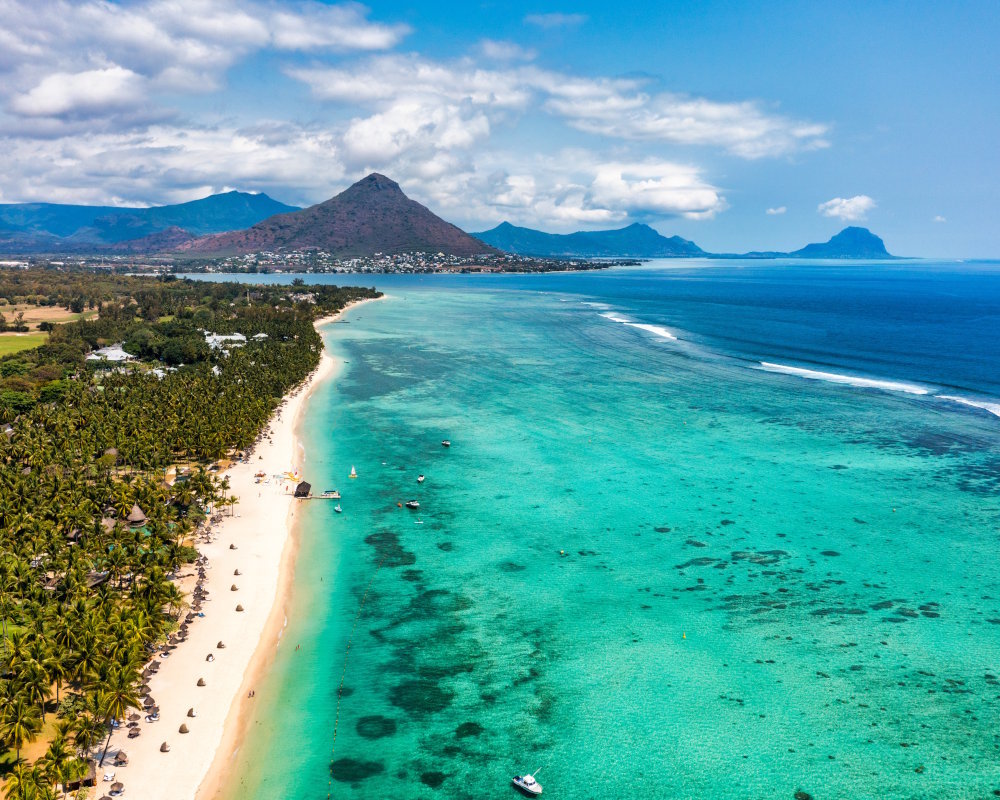 La plage de sable blanc de Flic en Flac avec le Piton de la Petite Rivière Noire, point culminant de l'île Maurice, en arrière-plan