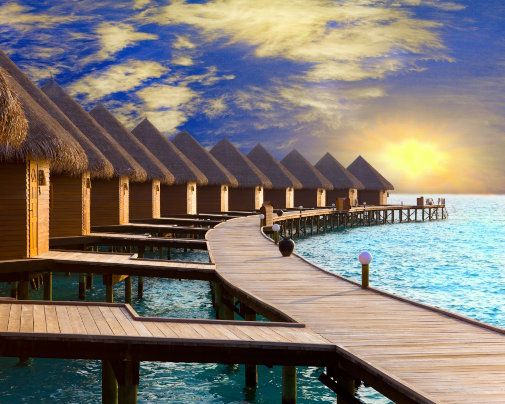 Villas sur pilotis aux Maldives au coucher du soleil, entourées par les eaux turquoise du lagon