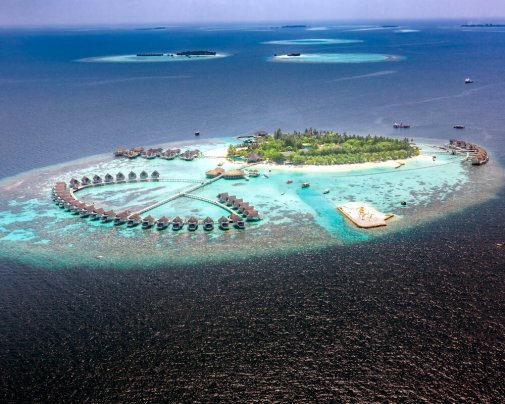 Vue aérienne de l'île de Machchafushi, dans l'atoll d'Ari aux Maldives, avec ses villas sur pilotis et son lagon
