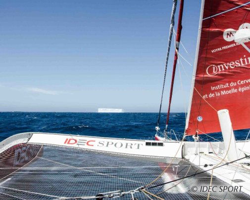 Le maxi trimaran IDEC SPORT glisse sur l'eau avec un iceberg géant en point de mire !