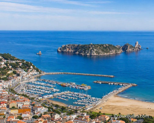 Aerial view of L'Estartit with its marina, wide sandy beach, and the Medes islands in the background