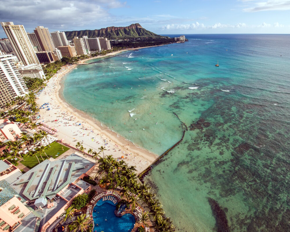 An aerial view of the Waikiki coastline with the famous Diamond Head crater in the background